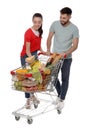 Happy couple with shopping cart full of groceries on white background Royalty Free Stock Photo