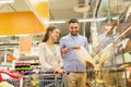 Happy couple with shopping cart at grocery store Royalty Free Stock Photo