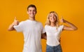 Happy couple showing thumbs up over yellow background