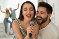 Happy couple singing karaoke with friends at home Royalty Free Stock Photo