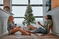 Happy couple sit relax on wooden floor in kitchen drinking red wine. Smiling young husband and wife rest at home enjoy romantic Royalty Free Stock Photo