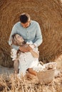 Happy couple sitting on bale in farmland Royalty Free Stock Photo