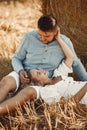 Happy couple sitting on bale in farmland Royalty Free Stock Photo