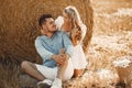 Happy couple sitting on bale in farmland Royalty Free Stock Photo