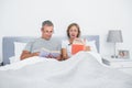 Happy couple sitting in bed reading books Royalty Free Stock Photo