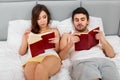 Happy Couple Sitting in Bed Reading Books at Home in Bedroom Royalty Free Stock Photo