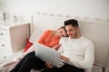 Happy couple sitting on bed using laptop Royalty Free Stock Photo