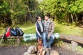 Happy couple sitting on bench near camp fire Royalty Free Stock Photo