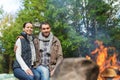 Happy couple sitting on bench near camp fire Royalty Free Stock Photo