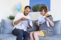 A happy couple sitting on the couch in the living room. Woman is pregnant, and they are watching baby clothes Royalty Free Stock Photo
