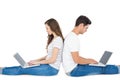 Happy couple sitting on the floor back to back using laptop Royalty Free Stock Photo