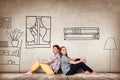 Happy couple sitting on the floor among painted furniture on the wall. Royalty Free Stock Photo