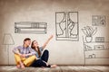 Happy couple sitting on the floor among painted furniture on the wall. Royalty Free Stock Photo