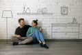 Happy couple sitting on floor and planning new home interior. furniture sketch Royalty Free Stock Photo