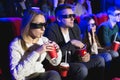 Happy couple sitting in movie theater, watching 3D movie, eating popcorn. Royalty Free Stock Photo