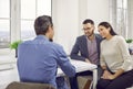 Happy couple sitting at an office desk and talking to a real estate agent or bank manager Royalty Free Stock Photo