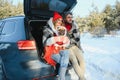 Happy couple sitting in open car back, having stop off. Romantic traveling concept. Winter forest Royalty Free Stock Photo