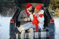 Happy couple sitting in open car back, having stop off. Romantic traveling concept. Winter forest Royalty Free Stock Photo