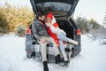 Happy couple sitting in open car back, having stop off. Romantic traveling concept. Winter forest Royalty Free Stock Photo