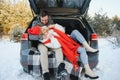 Happy couple sitting in open car back, having stop off. Romantic traveling concept. Winter forest Royalty Free Stock Photo