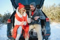 Happy couple sitting in open car back, having stop off. Romantic traveling concept. Winter forest Royalty Free Stock Photo