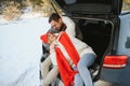 Happy couple sitting in open car back, having stop off. Romantic traveling concept. Winter forest Royalty Free Stock Photo