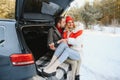 Happy couple sitting in open car back, having stop off. Romantic traveling concept. Winter forest Royalty Free Stock Photo