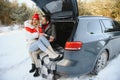 Happy couple sitting in open car back, having stop off. Romantic traveling concept. Winter forest Royalty Free Stock Photo