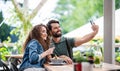 Happy couple sitting outdoors on terrace restaurant, taking selfie. Royalty Free Stock Photo