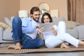 Happy couple sitting and planning new home decoration at home with a tablet Royalty Free Stock Photo