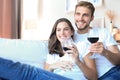 Happy couple sitting, relaxing on couch in living room, using laptop for online shopping together Royalty Free Stock Photo