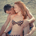 Happy couple sitting on sandy beach embracing & kissing Royalty Free Stock Photo