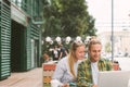 Happy couple sitting in street cafe together and using laptop Royalty Free Stock Photo