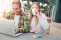 Happy couple sitting in street cafe together and using laptop, woman drinking Royalty Free Stock Photo