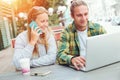 Happy couple sitting in street cafe together, woman talking on the phone and man using laptop Royalty Free Stock Photo