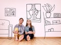 Happy couple sitting in their new flat among painted furniture on the wall. Royalty Free Stock Photo