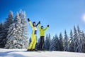 Happy couple skiers posing on skis before skiing at ski resort. Clear blue sky, snow-covered fir trees on background. Royalty Free Stock Photo