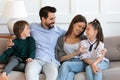 Happy couple with small son listening to adorable schoolgirl daughter.