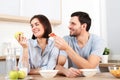 Happy couple spend free time or weekend together at kitchen, glad husband suggests wife to eat snack, she refuses as
