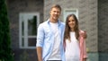 Happy couple standing against new bought house, real estate agency advertisement