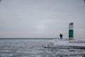 Happy couple standing on frozen pier next to lighthouse