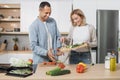 Happy couple standing in modern kitchen cooking salad breakfast or dinner together. Royalty Free Stock Photo