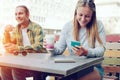 Happy couple in street cafe together, smiling woman using mobile phone, outdoors Royalty Free Stock Photo