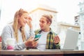 Happy couple in street cafe together, using smartphone and laptop, surprised man Royalty Free Stock Photo