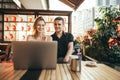 Happy couple of students sitting with laptop in cafe and sunset, looking at screen and smiling. Beautiful young man and girl Royalty Free Stock Photo