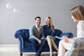 Happy couple at successful visit psychologist, smiling wife and husband sitting together on couch