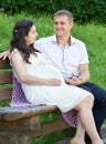 Happy couple in summer city park outdoor, pregnant woman, bright sunny day and green grass, beautiful people portrait Royalty Free Stock Photo