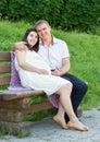 Happy couple in summer city park outdoor, pregnant woman, bright sunny day and green grass, beautiful people portrait Royalty Free Stock Photo