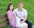 Happy couple in summer city park outdoor, pregnant woman, bright sunny day and green grass, beautiful people portrait Royalty Free Stock Photo