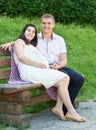 Happy couple in summer city park outdoor, pregnant woman, bright sunny day and green grass, beautiful people portrait Royalty Free Stock Photo